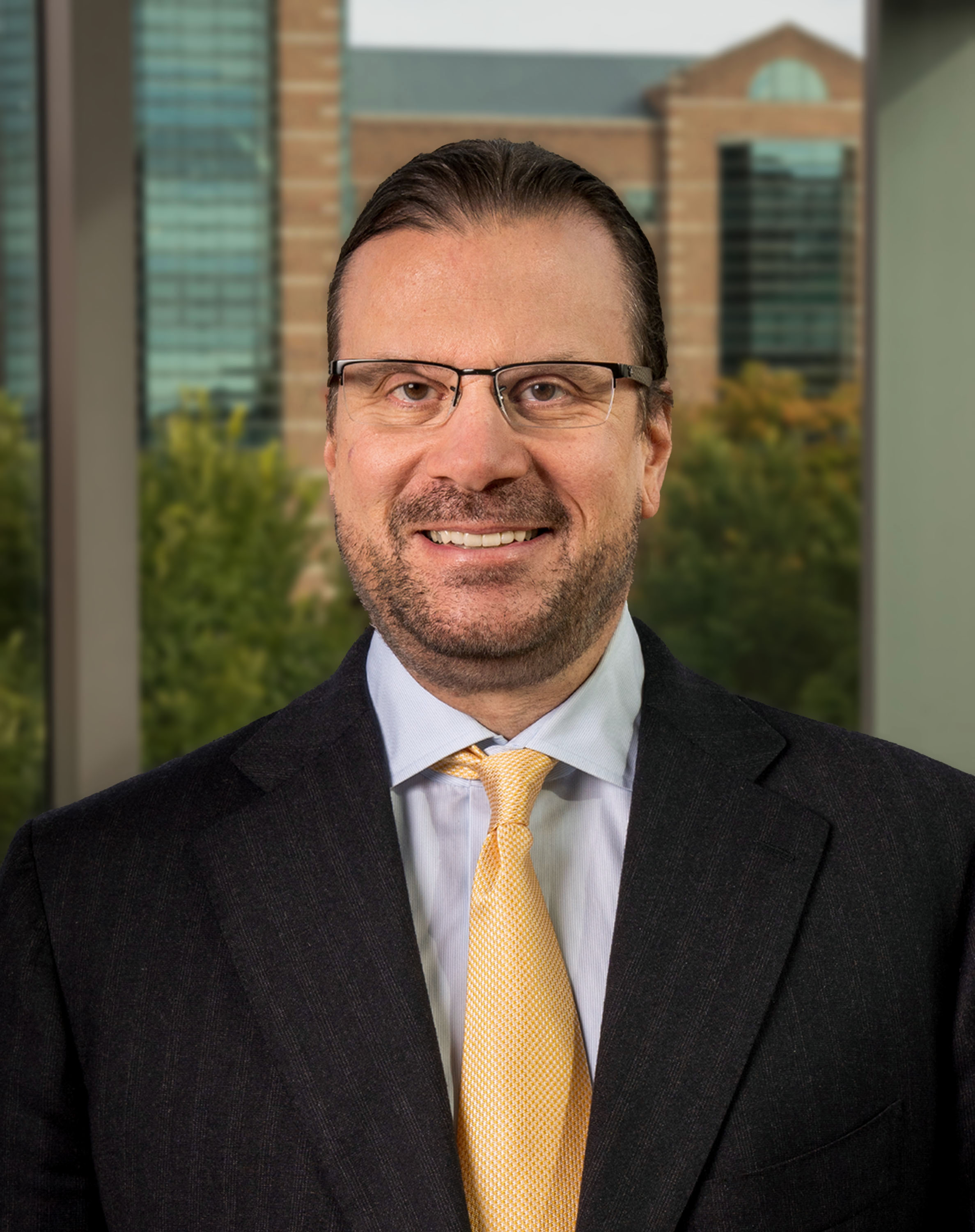 Man with long hair wearing glasses and a suit